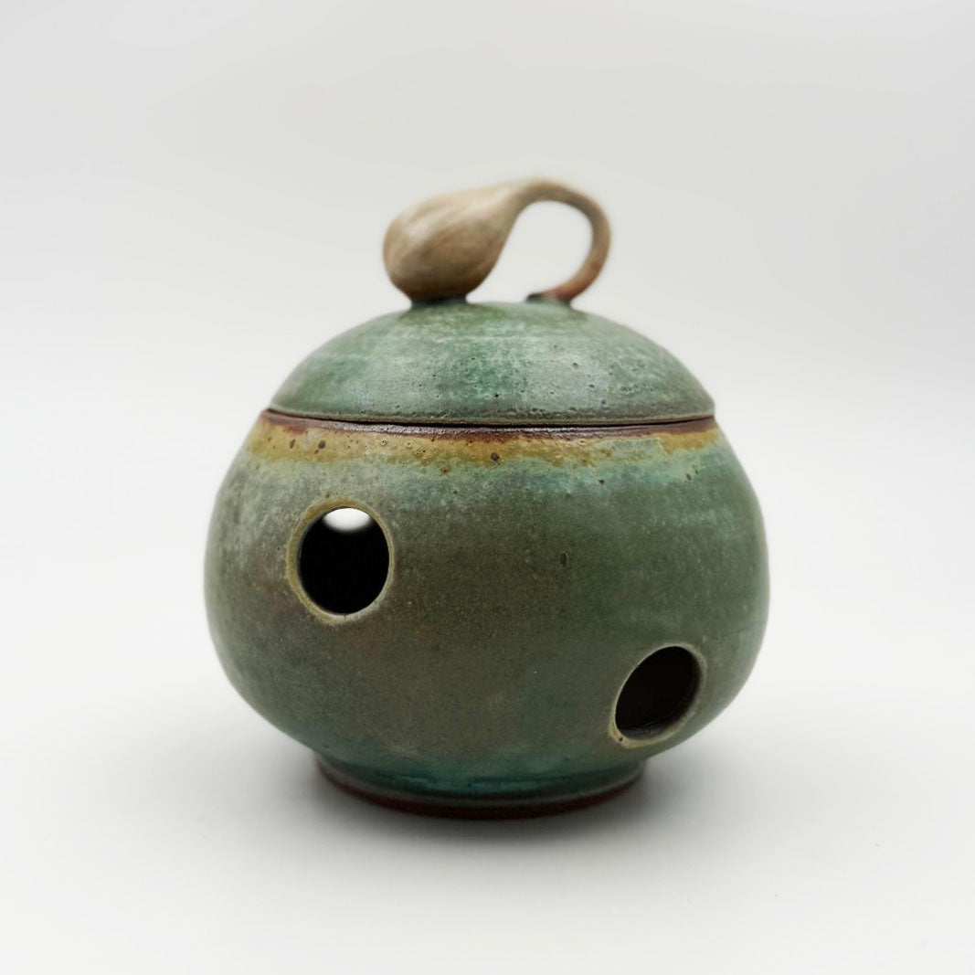 Green ceramic jar with a lid on a white background