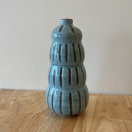 A blue ceramic vase with a textured surface, displayed against a neutral background.