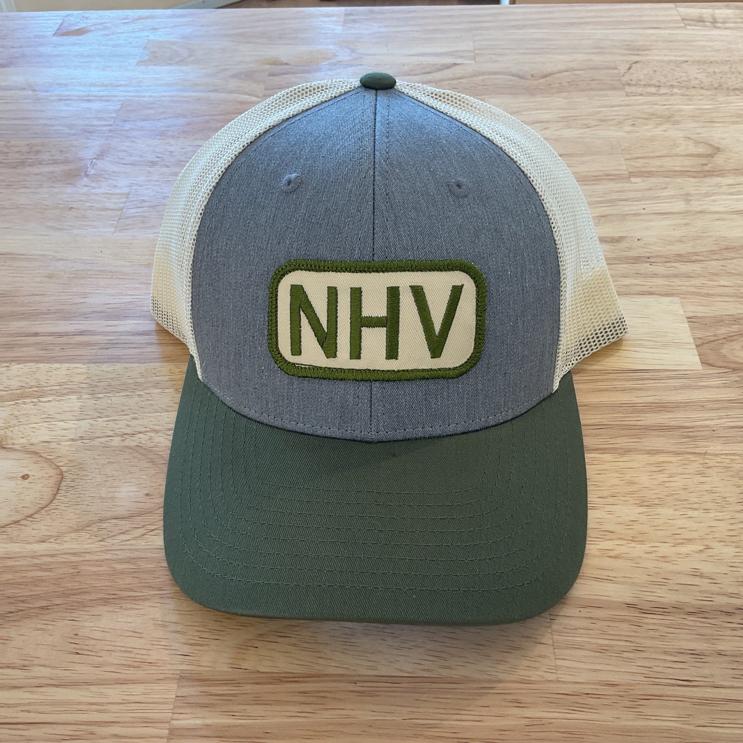 Trucker hat with 'NHV' logo on a wooden surface