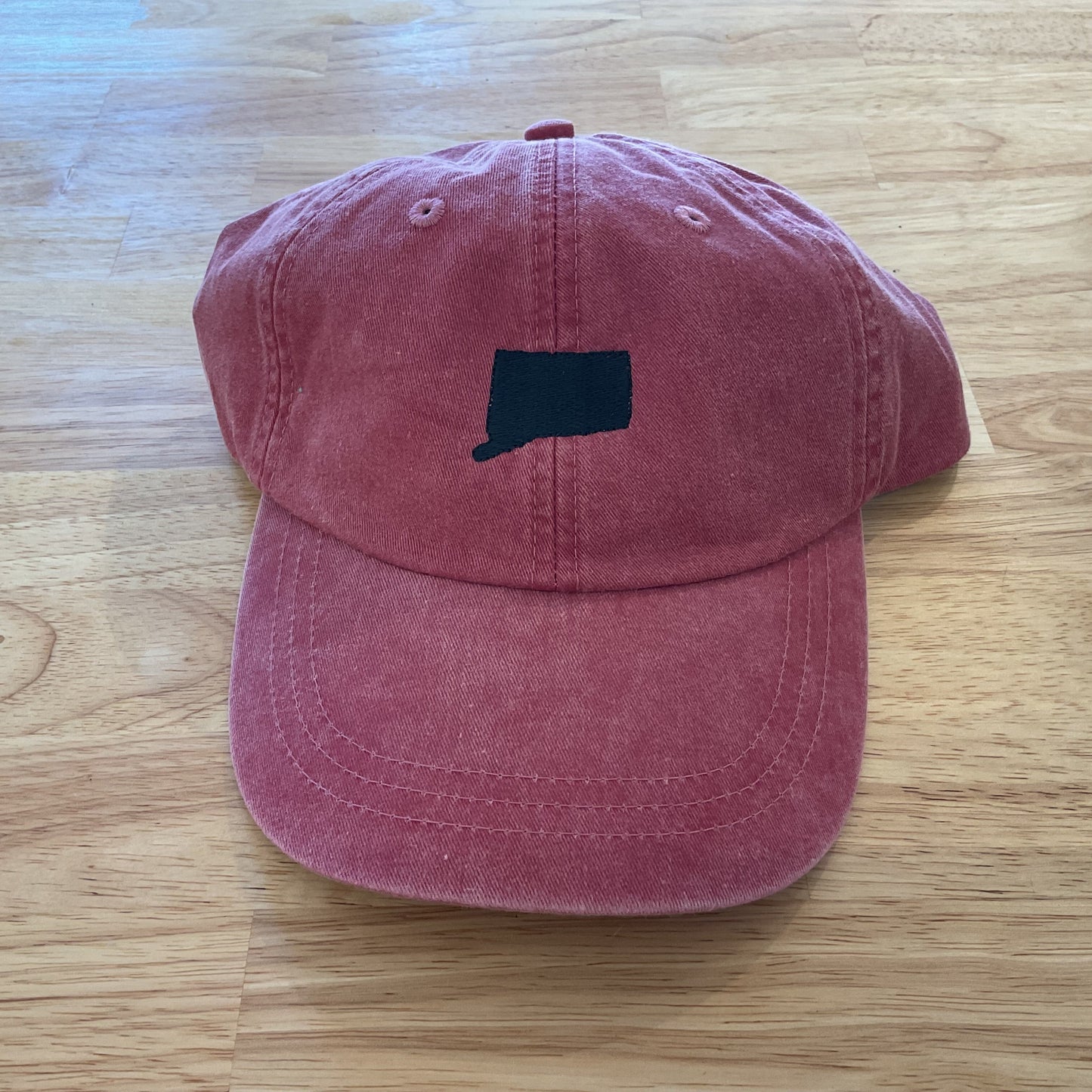 Pink cap with a black logo on a wooden surface