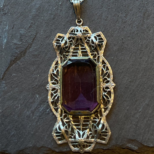 Necklace with a purple gemstone on a textured surface