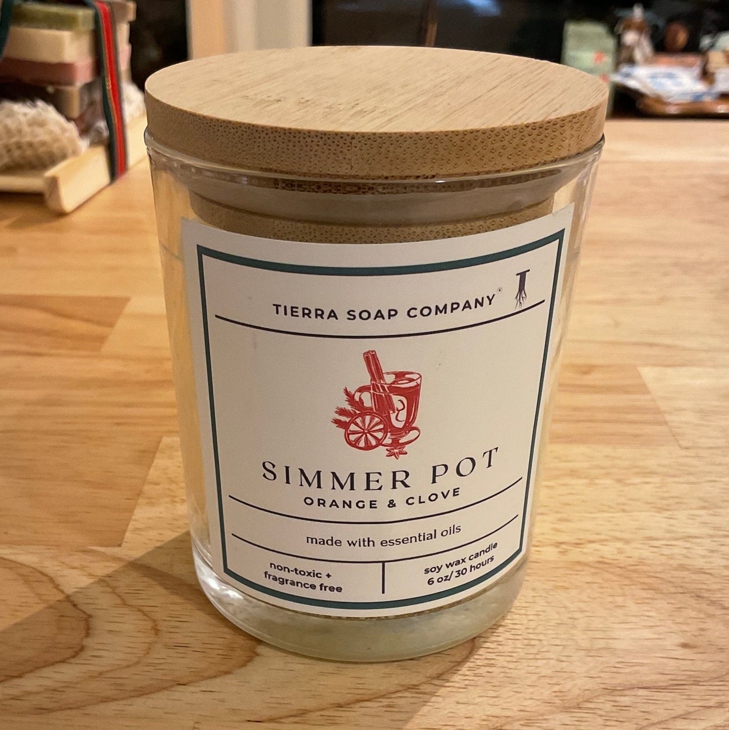 Jar labeled 'Simmer Pot' on a wooden surface with a blurred background