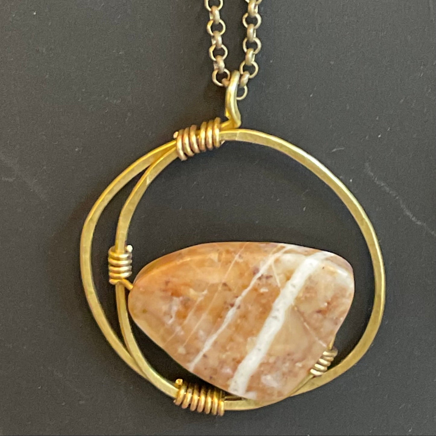 Necklace with a stone pendant in a gold circular frame on a dark background