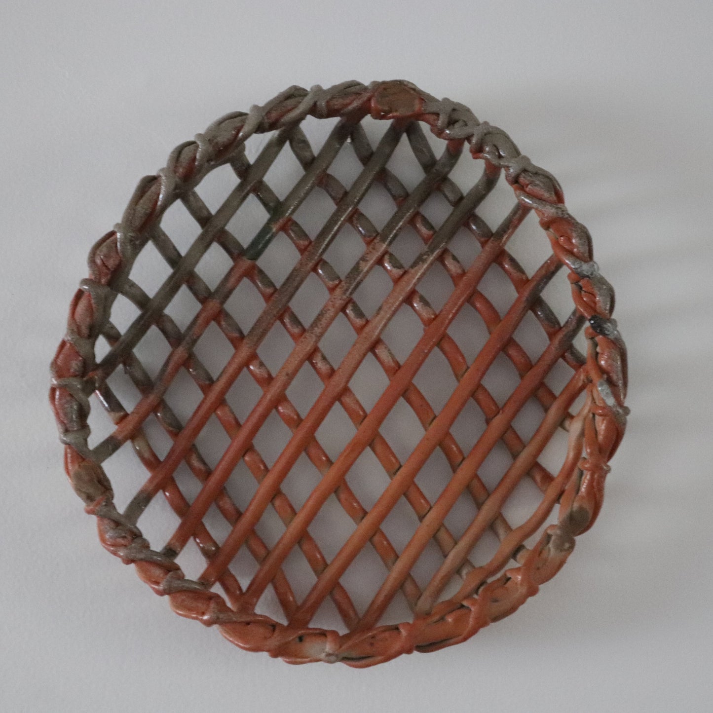 Round woven basket with a lattice pattern on a white background