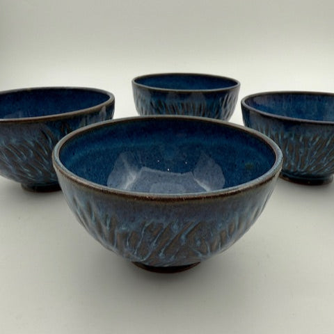 A set of blue ceramic bowls with carved details on a white background.