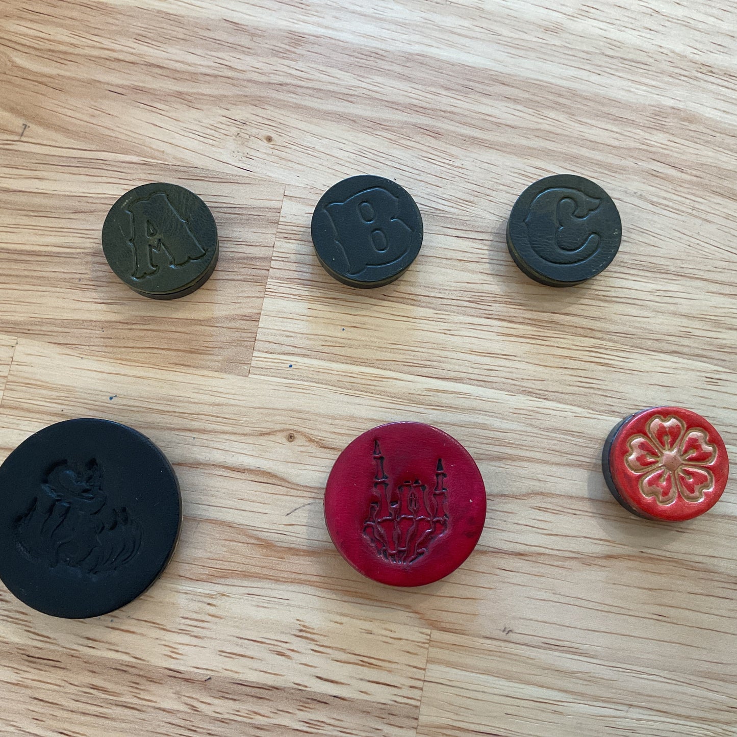 Six round stamps with different designs on a wooden surface