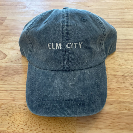 Blue cap with 'ELM CITY' text on a wooden surface