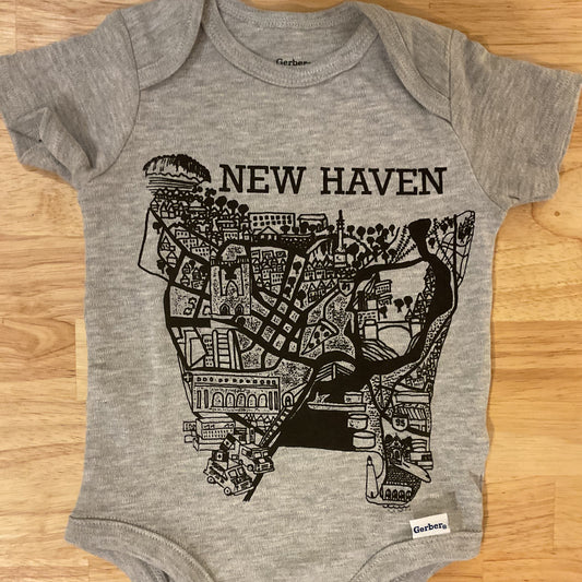 Gray baby onesie with black map design and 'New Haven' text on a wooden surface