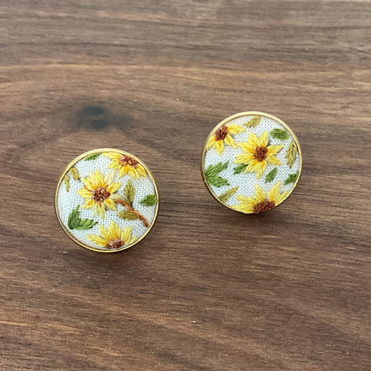 Round floral earrings on a wooden surface