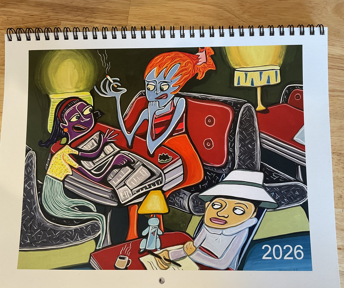 Colorful abstract artwork on a spiral-bound notebook with '2026' printed on it, placed on a wooden surface.