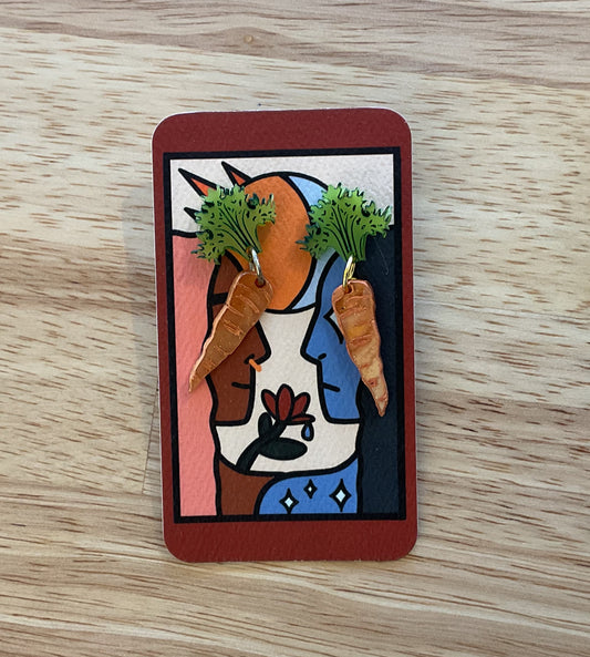Card with a colorful design featuring a face, carrots, and a cat on a wooden surface