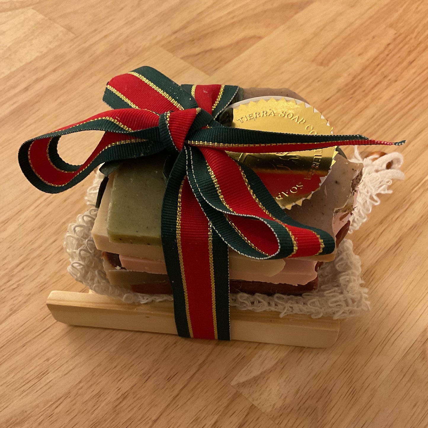 Small wooden box with a red and green ribbon on a wooden surface
