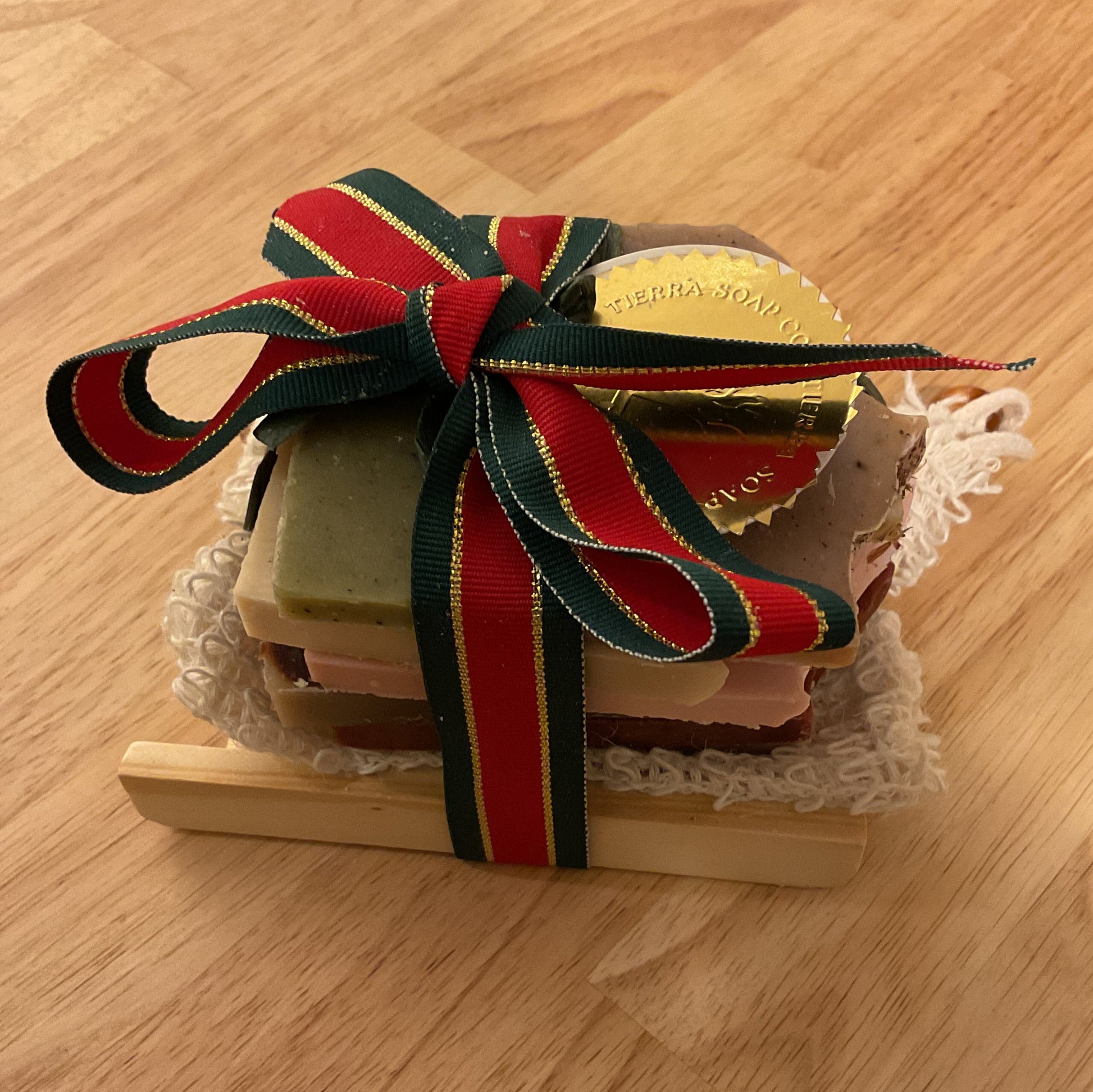 Small wooden box with a red and green ribbon on a wooden surface
