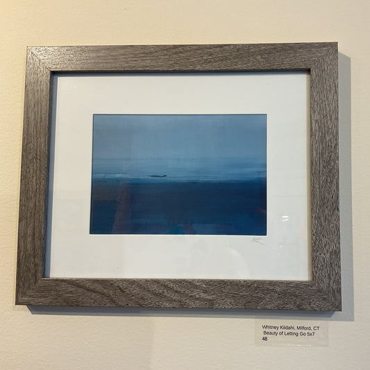 Framed photograph of a sunset over water on a beige wall