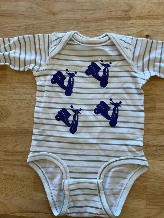Striped baby onesie with blue scooter designs on a wooden surface