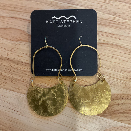 Gold earrings on a Katie Stephen Jewelry card on a wooden surface