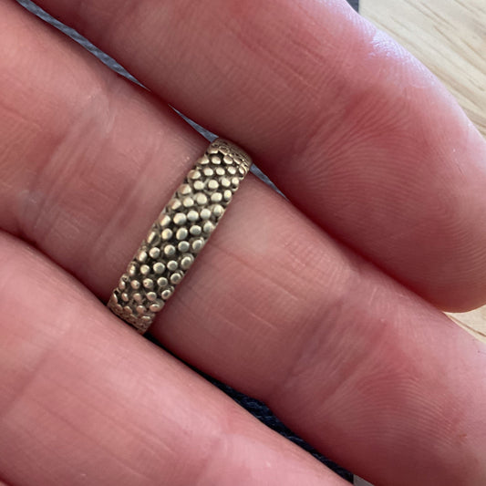 Gold ring on a finger with a light wooden background